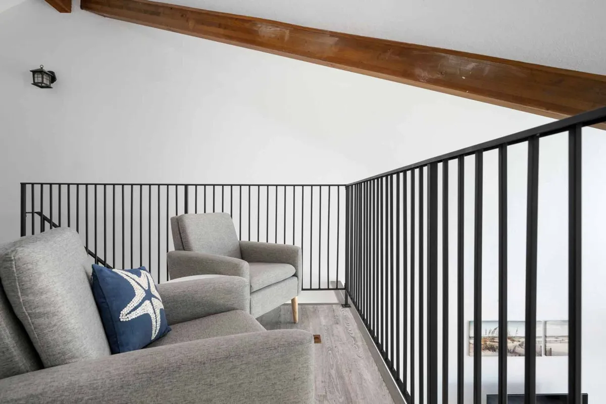 A tranquil nook featuring two armchairs (one with a starfish motif pillow), a black railing, and an adjacent window suggesting access to the balcony and outdoor views. The space is perfect for quiet conversations, reading, or enjoying the fresh air.